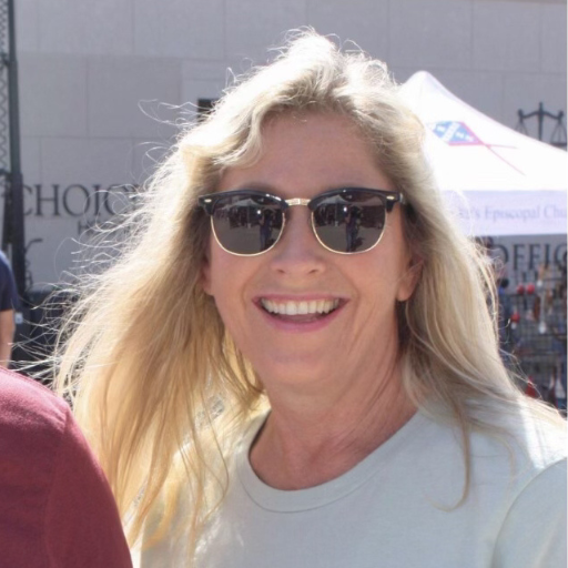 Tracy Caraway smiling outdoors with blonde hair and sunglasses